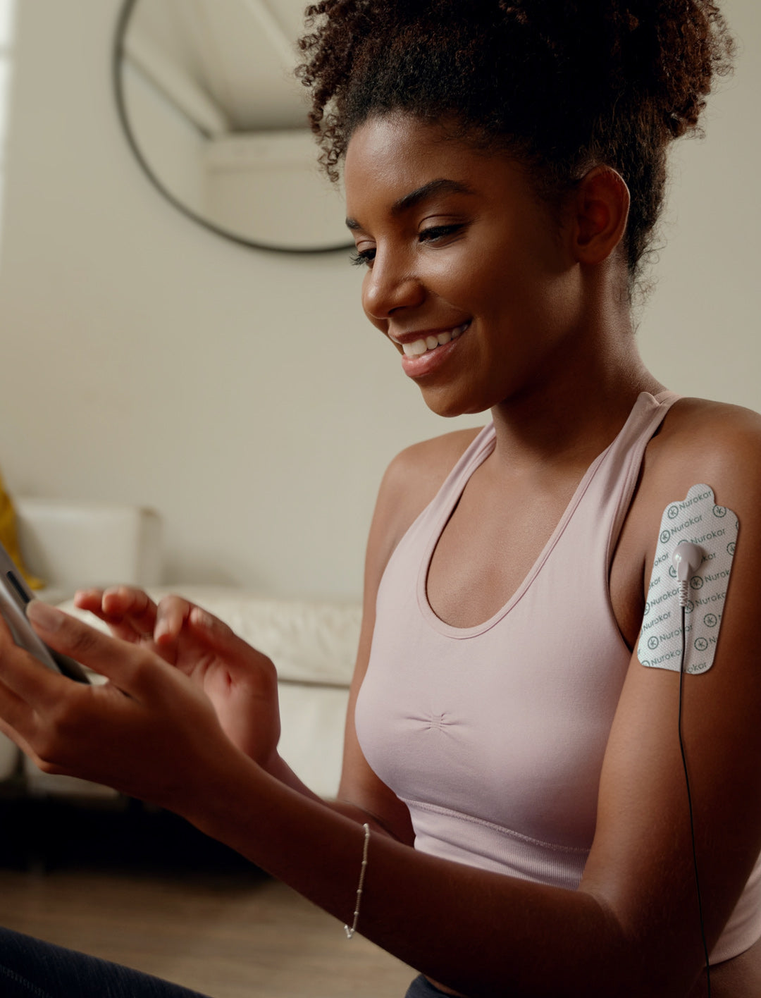 Lady using the mitouch and large electrode pads on her shoulder after working out, exercise recovery, shoulder pain, muscle repair