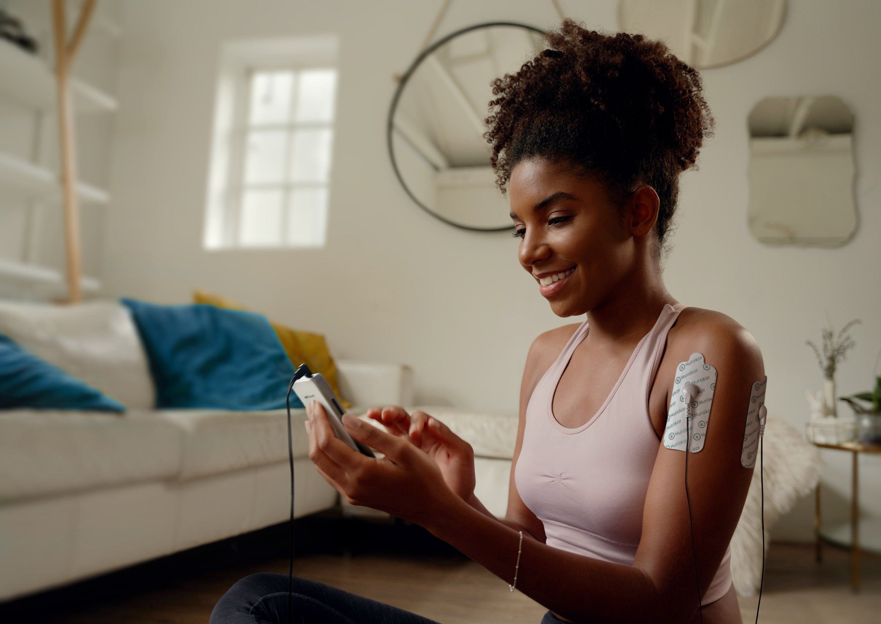 Lady using the mitouch and large electrode pads on her shoulder after working out, exercise recovery, shoulder pain, muscle repair