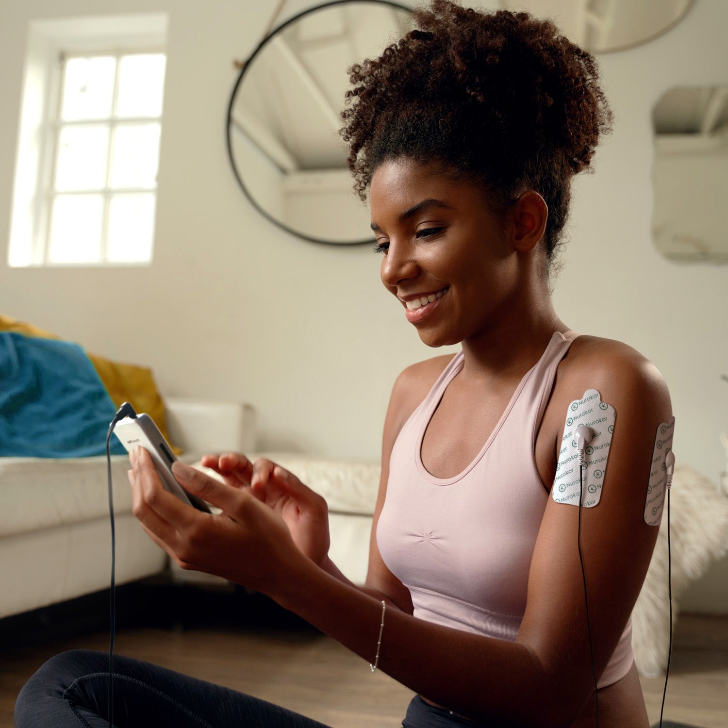 Lady using the mitouch and large electrode pads on her shoulder after working out, exercise recovery, shoulder pain, muscle repair
